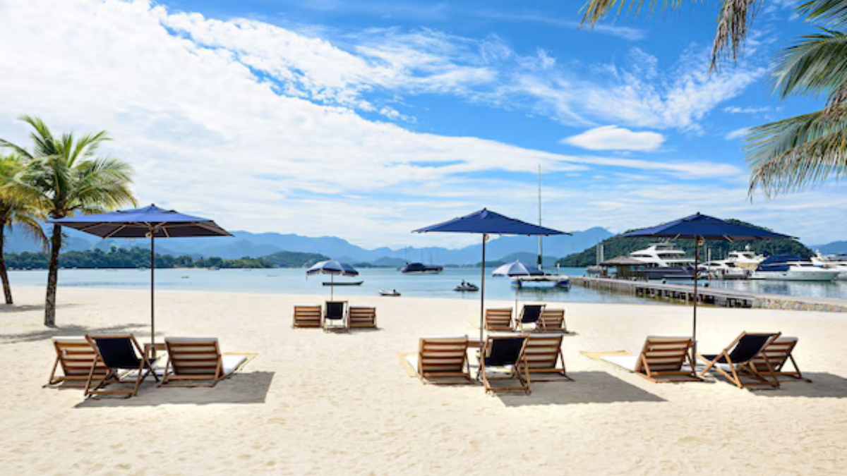 Vista aérea do Hotel Fasano Angra dos Reis, mostrando piscinas, vegetação da Mata Atlântica e o mar azul da Costa Verde ao fundo.